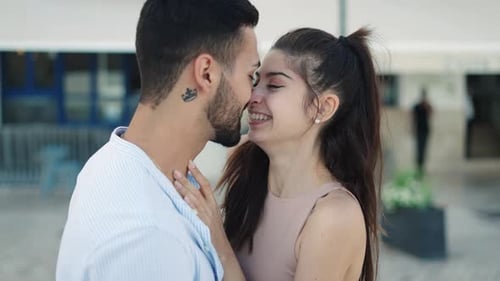 Smiling Hispanic Couple Talking and Kissing on Street