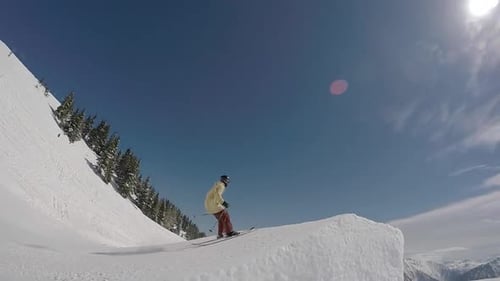 Ein junger Mann, der beim Skifahren und Abfahren fährt, springt in einem Geländepark auf einem schneebedeckten Berg.