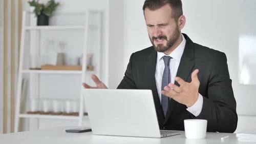 Businessman Frustrated While Typing on Laptop Computer