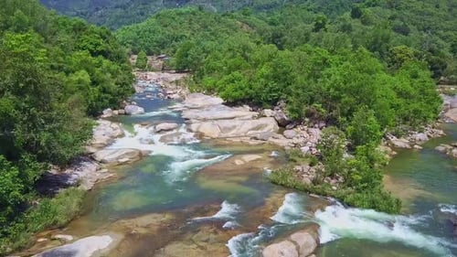 Drone Flies Up Narrow River with Rapids Rocky Banks