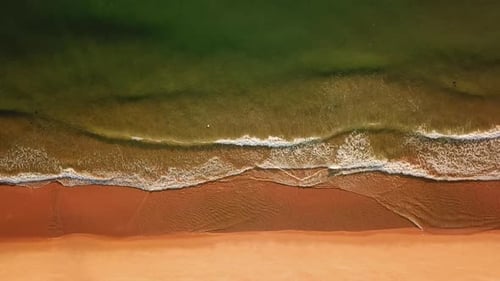 Drone View of Sea Foam Waves, Beating Against Sandy Seashore.