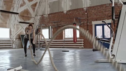 Sportive tatouée faisant un exercice de bras de corde de combat