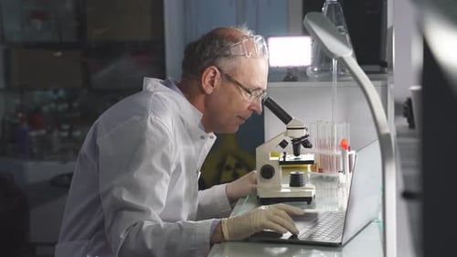 Scientist Works with Microscope in Lab