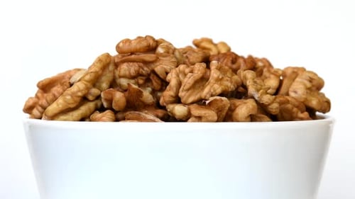 Walnuts in bowl rotating close-up on white background