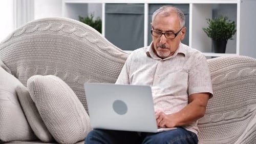 Senior Man Using Laptop at Home on Couch