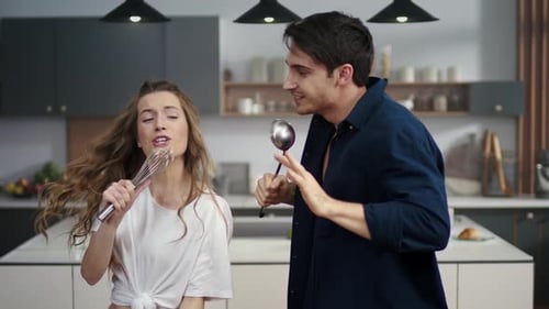 Energetic Couple Dancing in Kitchen with Kitchen Utensils