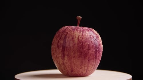 Ein ganzer roter Apfel mit einem Stiel liegt auf einer Holzoberfläche