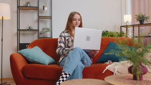 Young Woman Working on Laptop on Couch at Home