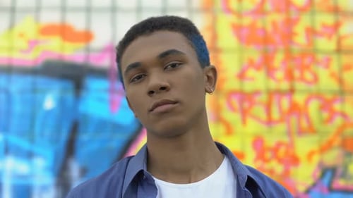 Coole männliche Teenager mit farbigen Haaren aussehende Kamera auf Graffiti-Wandhintergrund