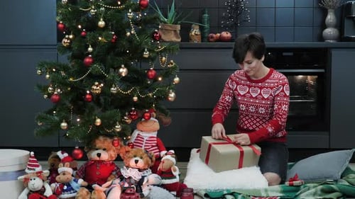 Woman Prepares Christmas Gift Under Decorated Tree