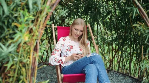 Young Woman Using Smartphone in Plant Gazebo