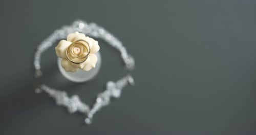Gold Wedding Bands on Flower with Jeweled Necklace