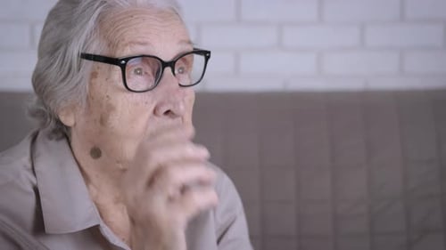 Senior Woman Putting on Eyeglasses Indoors