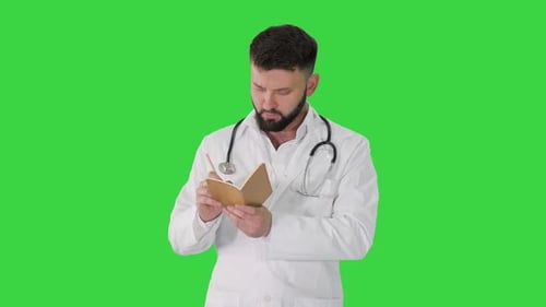 Turk Doctor Holding Pen and Notebook Looking for Idea on a Green Screen, Chroma Key