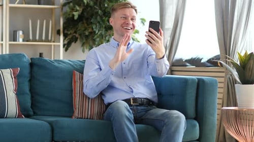 Smiling Man Video Calling on Smartphone at Home
