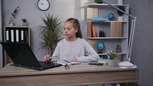 Focused Girl Studying at Desk with Laptop