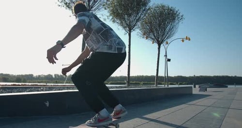 Skater Is Doing a Rail Slide on a Tall Curb at the Park in the Morning,