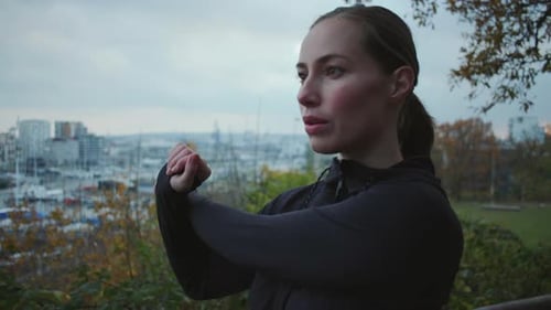 Woman Stretching Arms in Park Overlooking City