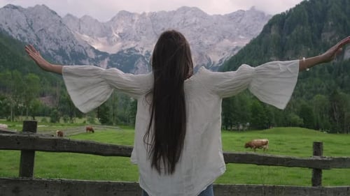 Woman Looking at Country Scene with Cows and Alps