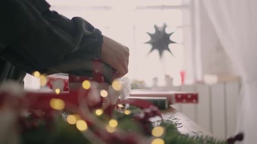 Woman arranging Christmas present in festive setting