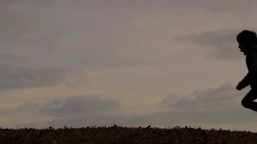 Criança em silhueta enquanto corre em um prado