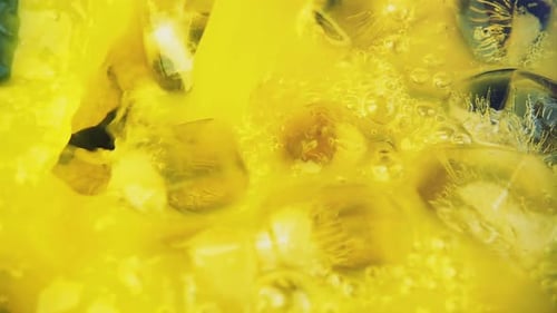Refreshing Yellow Liquid Poured Over Ice Cubes