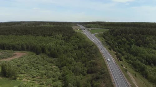 Luftbild eines weißen Lastwagens, der eine stark befahrene Autobahn/Autobahnüberführung/Overdrive/Brücke passiert