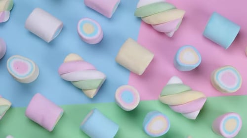 Rotierende mehrfarbige zähe Marshmallows auf mehrfarbigem Hintergrund - das Konzept eines Geburtstages
