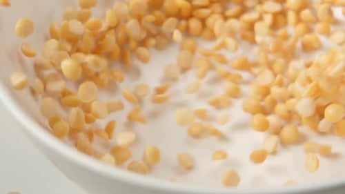 Yellow Split Peas Pouring into White Bowl Close-up