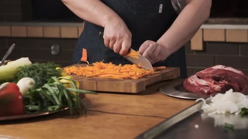 Chef in Restaurant Kitchen Cuts Carrot with Sharp Shiny Knife