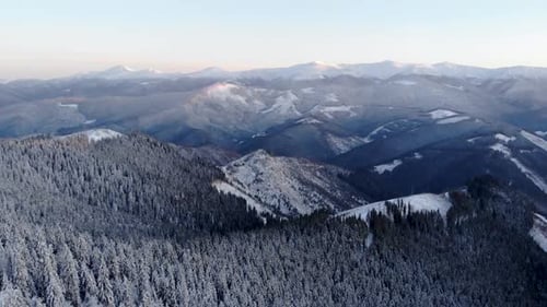 Vol aérien par drone au-dessus de la forêt hivernale dévoilant une vallée de montagne