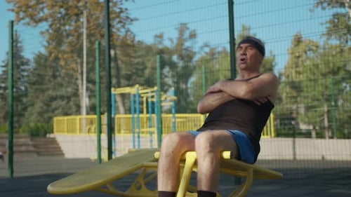 A Retired Elderly Man Works Out on a Sports Ground Outside. Healthy Lifestyle Concept.