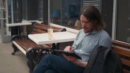 Young Adult Uses Tablet on Urban Bench