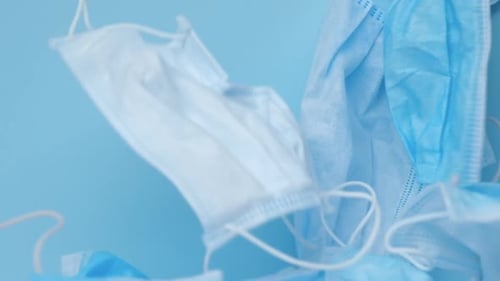 Pile of Disposable Surgical Face Masks on Blue Surface