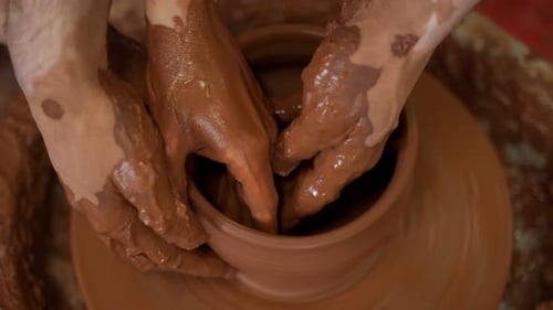 Enseignement de la poterie Un artisan guide la main d'une femme montrant comment lancer un pot en argile sur un potier