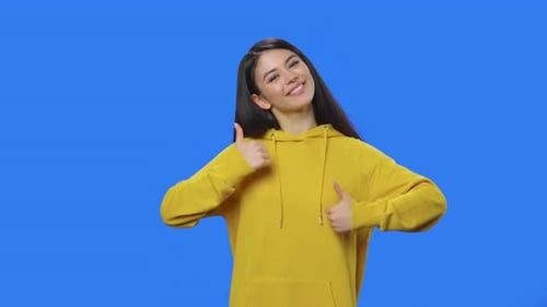 Smiling Woman Gives Two Thumbs Up on Blue