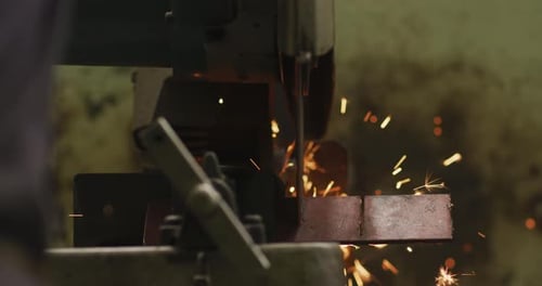 Detail eines kaukasischen Fabrikarbeiters in einer Fabrik, der an einer Werkbank steht und ein Metall schneidet
