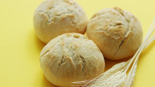 Fresh Bread Rolls with Wheat on Yellow Surface