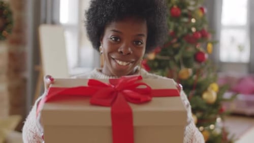 Woman Holds Christmas Gift with Red Ribbon