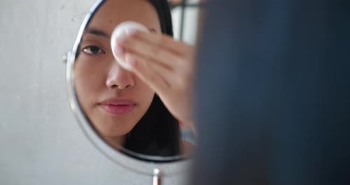 Young Woman Cleansing Face with Cotton Pad