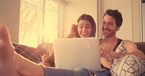 Couple Relaxing Indoors Laughing at Laptop Together