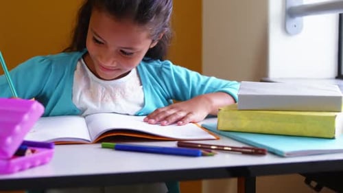 Schoolgirl doing homework in classroom at school