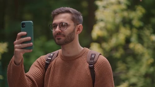 Young Man Using Smartphone Outdoors in Nature