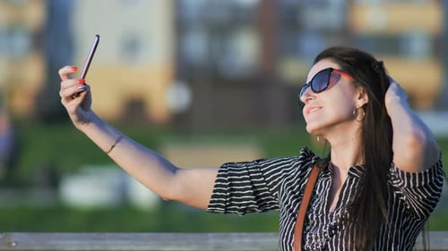 Beautiful Young Woman Taking Selfie in the Park with a Smartphone