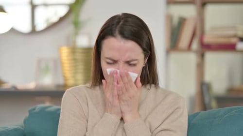 Young Woman Sits on Couch Using Tissue