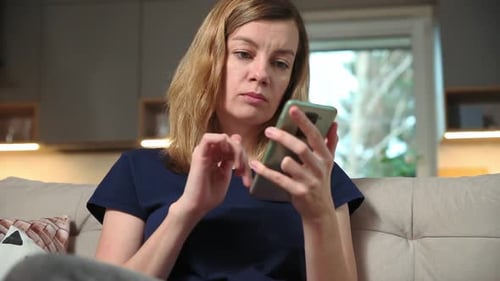 Woman Using Smartphone on Couch at Home