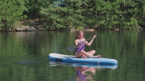 Young Fitness Woman Paddling Along Lake