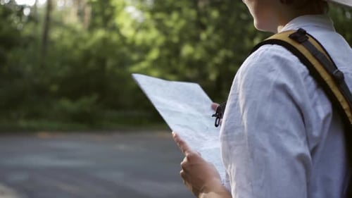 A Tourist Girl Is In The Forest Hiking, Stands Opposite The Sun In A Beautiful Big Hat, Looks