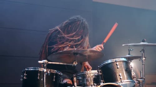 Un talentoso músico con rastas toca la batería en Smoke in a Club