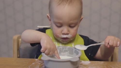Infant Eating Food With a Spoon at Table